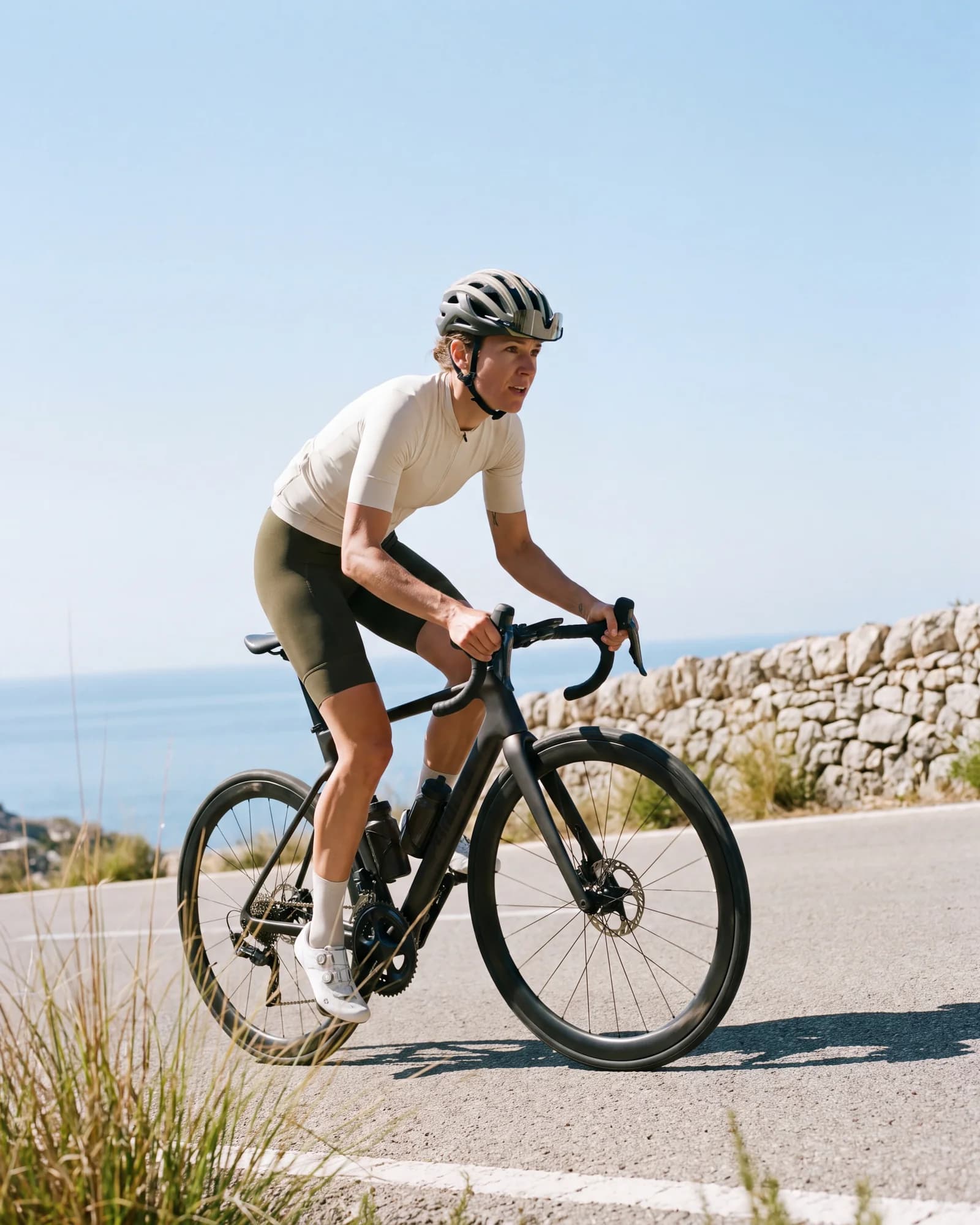A cyclist riding along a sunlit coastal road