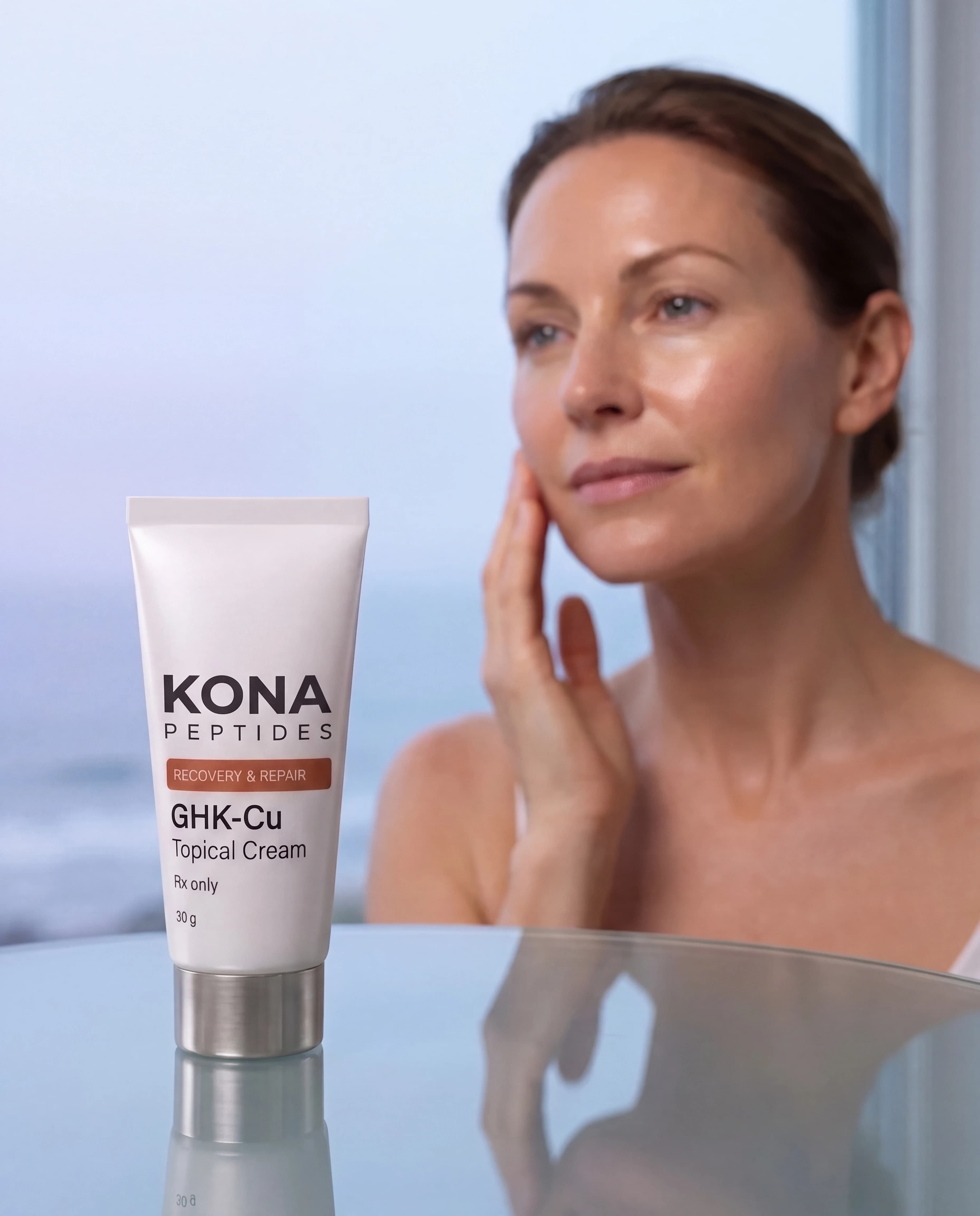 A GHK-Cu cream tube in front of a woman touching her cheek by a bright window