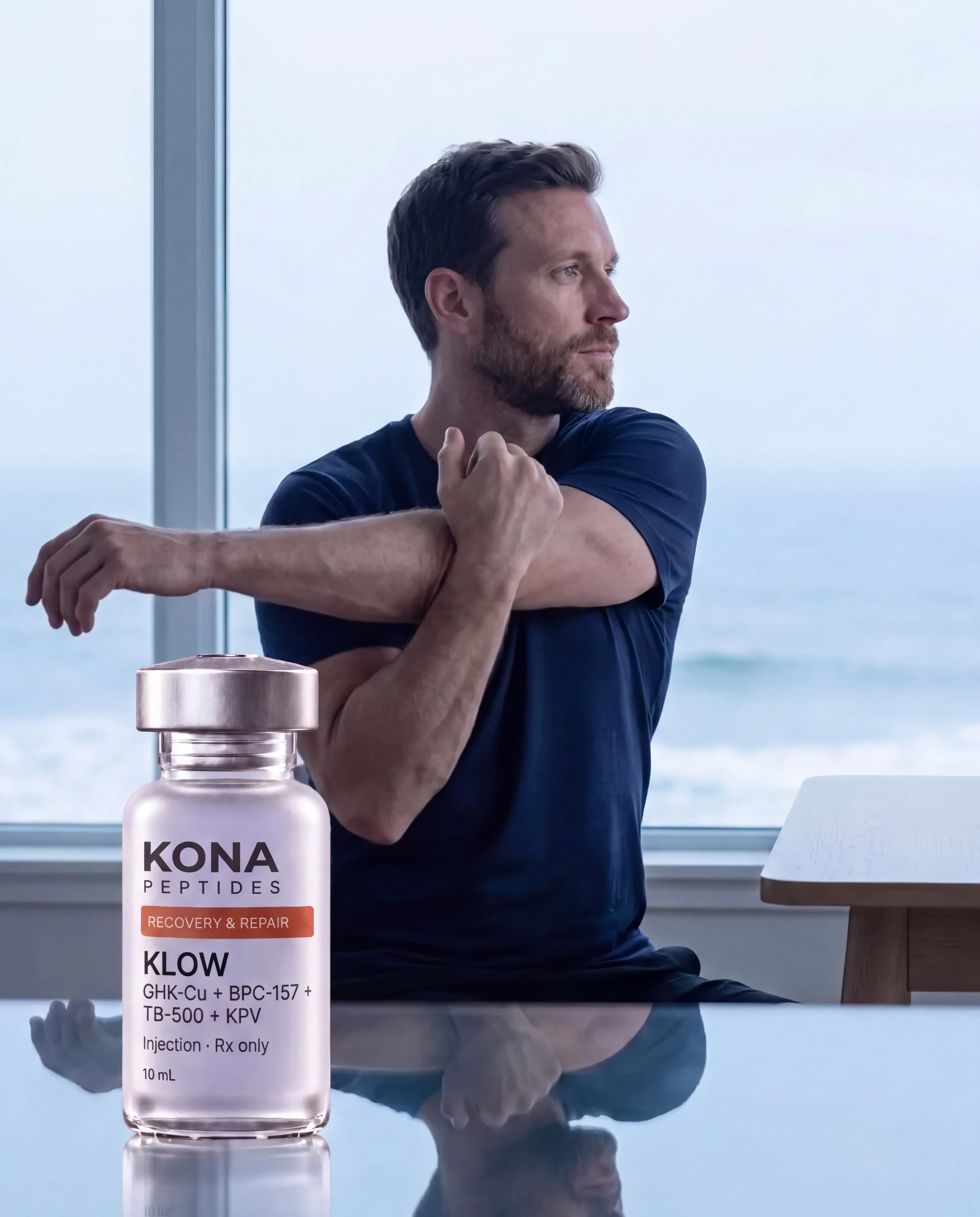 A KLOW vial in front of a man stretching his shoulder by a window over the sea
